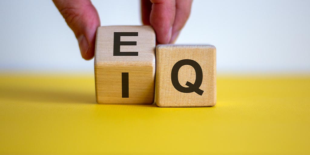 Hand flips a cube and changes the expression 'IQ' to 'EQ'